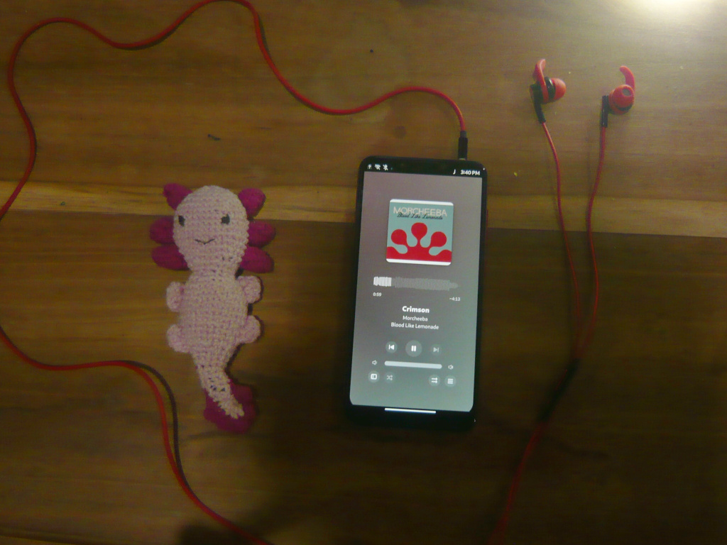 My Mobian phone connected up to earphones (with an amigurumi axolotl on the side)